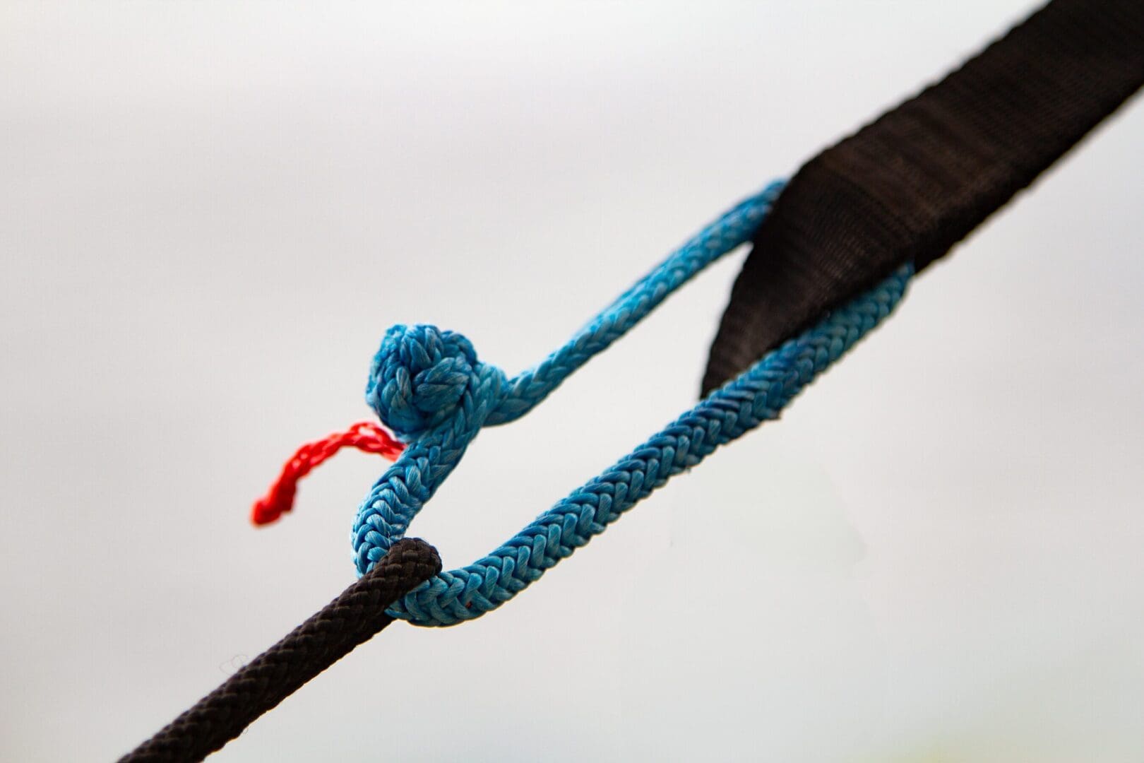 A blue rope is tied to the end of a black cord.